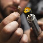 Close-up of a jeweler carefully working on a gold ring using a precision polishing tool. Expert craftsmanship in jewelry making.
